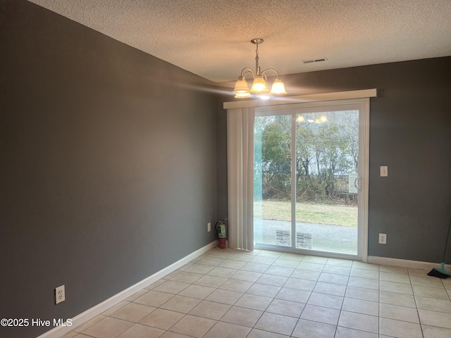 unfurnished room featuring a notable chandelier, light tile patterned floors, and a textured ceiling