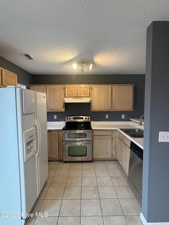 kitchen with sink, a textured ceiling, light brown cabinets, light tile patterned floors, and stainless steel appliances