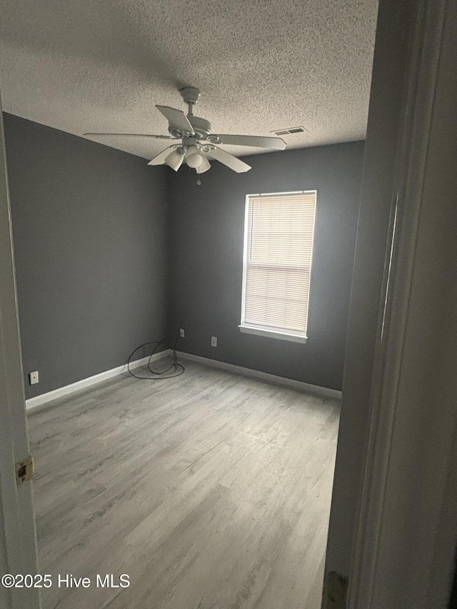 empty room featuring a textured ceiling, ceiling fan, and light wood-type flooring