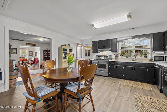 dining area featuring light wood-type flooring, crown molding, and sink