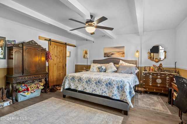 bedroom featuring wooden walls, ceiling fan, a barn door, beam ceiling, and wood-type flooring