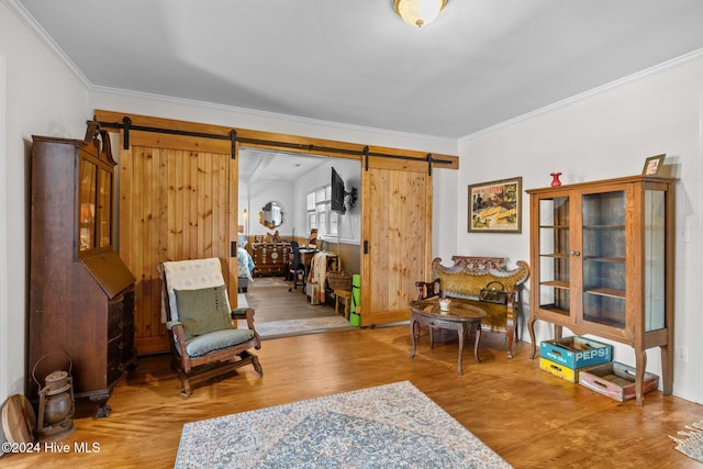 living area featuring a barn door, hardwood / wood-style floors, and ornamental molding