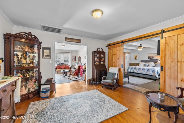 bedroom featuring a barn door, hardwood / wood-style flooring, and ornamental molding