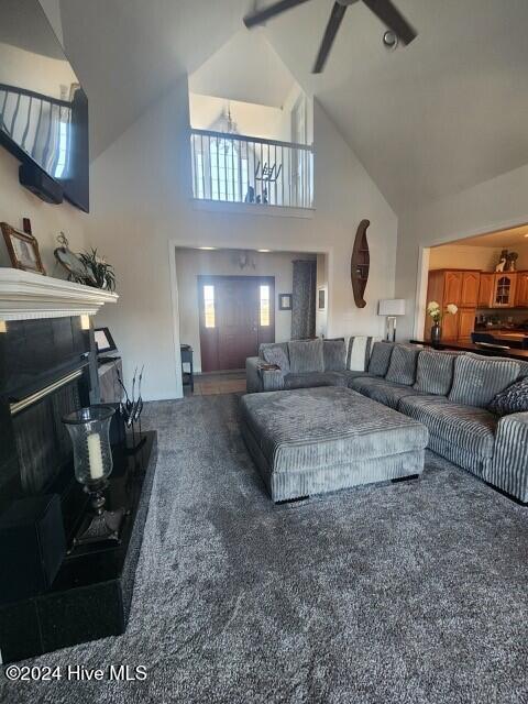 carpeted living room featuring a wealth of natural light, ceiling fan, and high vaulted ceiling