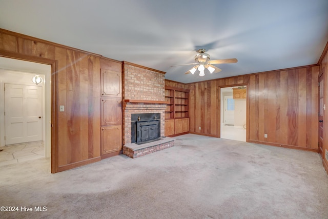 unfurnished living room featuring ceiling fan, light colored carpet, and wooden walls