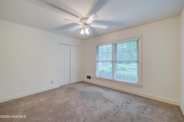 unfurnished bedroom with a closet, light colored carpet, and ceiling fan