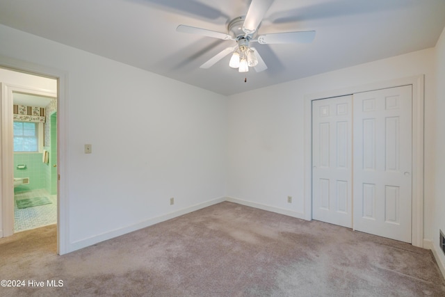 unfurnished bedroom featuring a closet, light colored carpet, and ceiling fan