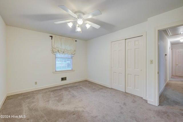 unfurnished bedroom with ceiling fan, light colored carpet, and a closet