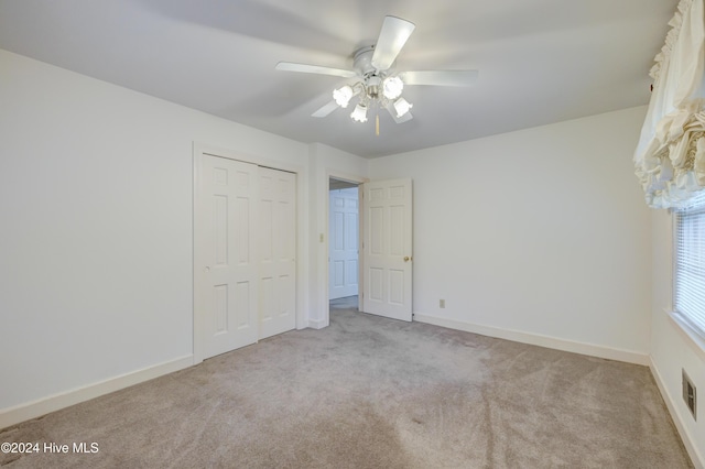 unfurnished bedroom featuring ceiling fan, light carpet, and a closet