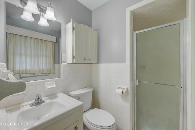 bathroom featuring a shower with door, vanity, tile walls, and toilet