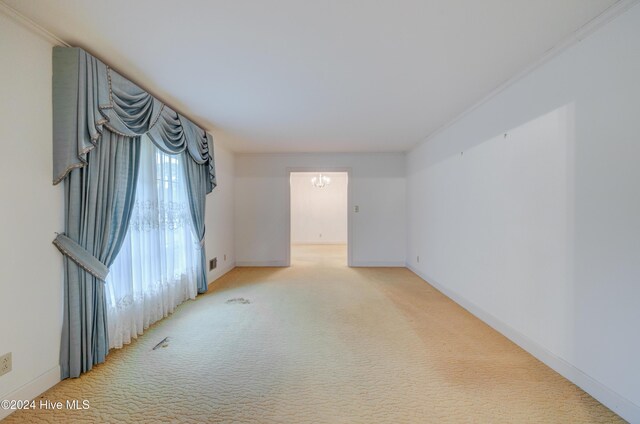 carpeted spare room featuring crown molding and an inviting chandelier