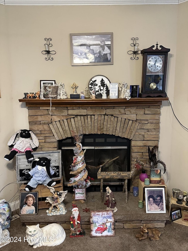 interior details featuring carpet flooring, a stone fireplace, and ornamental molding