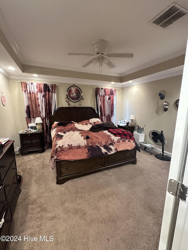 carpeted bedroom with ceiling fan, ornamental molding, and a tray ceiling