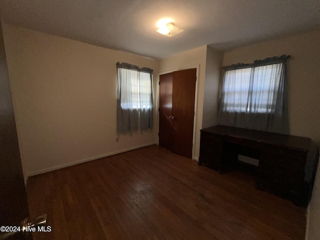 unfurnished bedroom with a closet and dark hardwood / wood-style floors