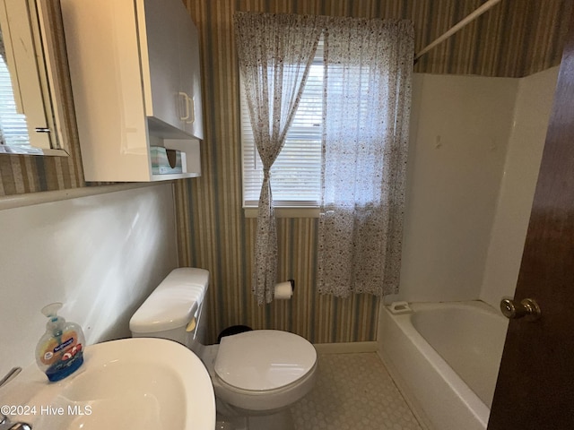 bathroom featuring a washtub, toilet, and sink