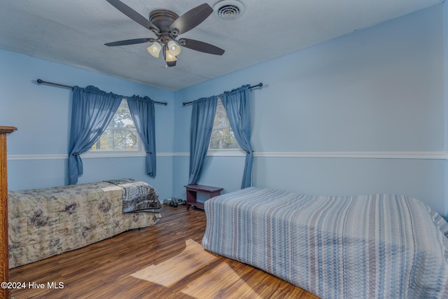 bedroom with a textured ceiling, hardwood / wood-style flooring, and ceiling fan