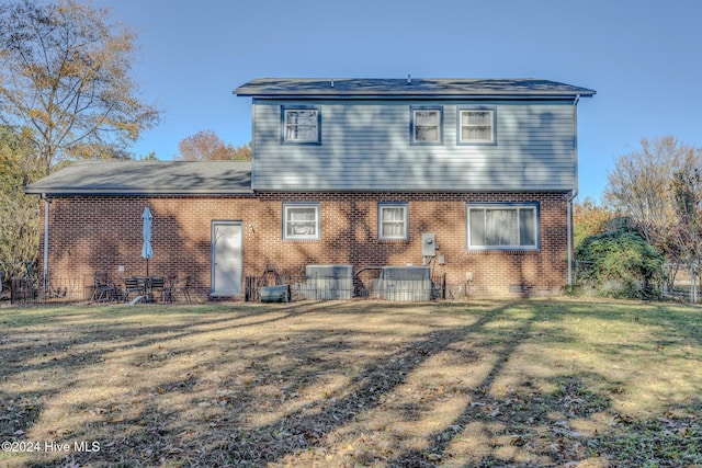 rear view of house with central AC and a yard