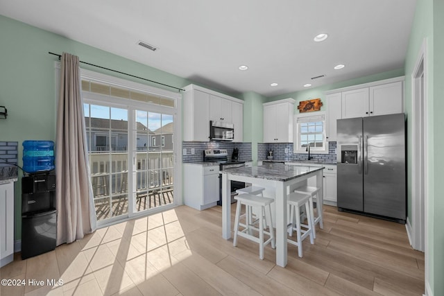 kitchen featuring light stone countertops, appliances with stainless steel finishes, a kitchen island, and plenty of natural light