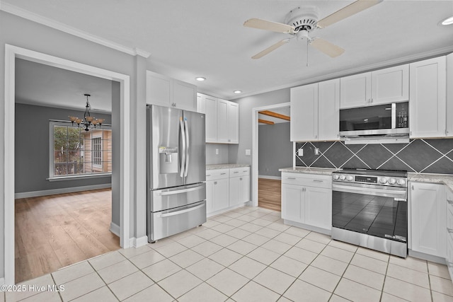 kitchen featuring ceiling fan with notable chandelier, decorative backsplash, light tile patterned floors, white cabinetry, and stainless steel appliances