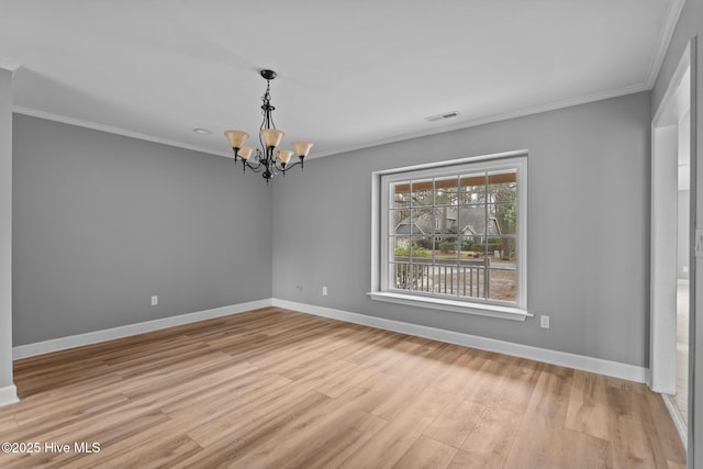 empty room featuring light hardwood / wood-style floors, a chandelier, and ornamental molding