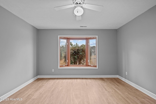 empty room with ceiling fan and light hardwood / wood-style flooring