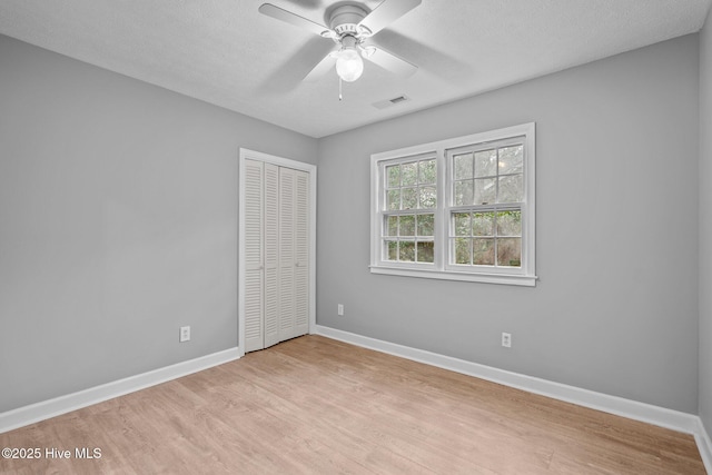 unfurnished bedroom featuring a textured ceiling, a closet, ceiling fan, and light hardwood / wood-style floors