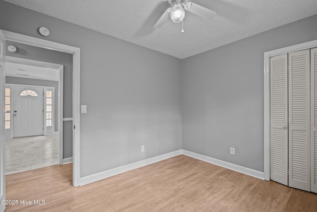 unfurnished bedroom with a textured ceiling, light wood-type flooring, a closet, and ceiling fan