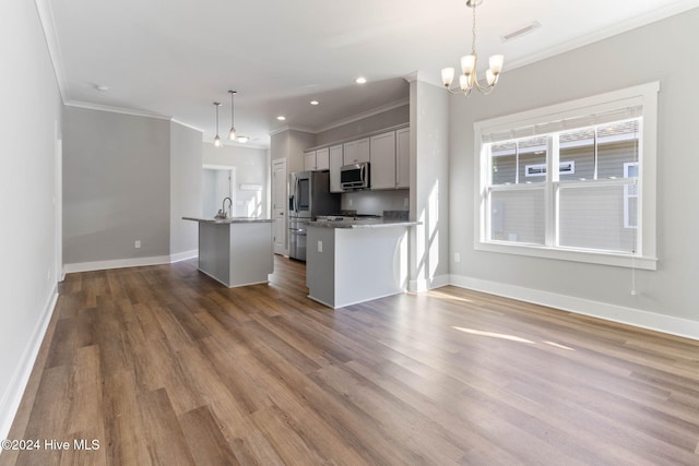 kitchen featuring appliances with stainless steel finishes, hanging light fixtures, ornamental molding, and hardwood / wood-style floors