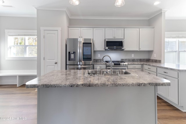 kitchen with a kitchen island with sink, white cabinets, crown molding, appliances with stainless steel finishes, and light hardwood / wood-style floors