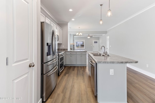 kitchen featuring ceiling fan, sink, hanging light fixtures, stainless steel appliances, and a kitchen island with sink