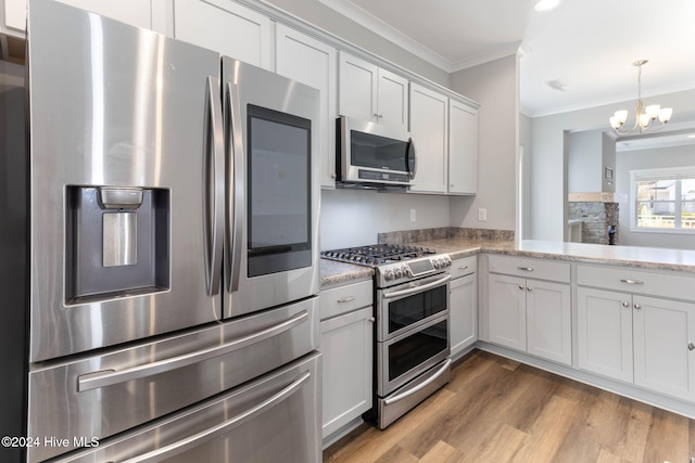 kitchen with appliances with stainless steel finishes, ornamental molding, a chandelier, hardwood / wood-style floors, and white cabinetry