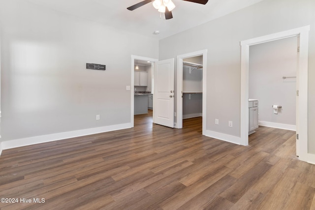 unfurnished bedroom featuring ensuite bathroom, ceiling fan, dark hardwood / wood-style floors, a spacious closet, and a closet