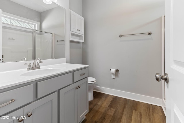 bathroom with hardwood / wood-style flooring, vanity, toilet, and an enclosed shower