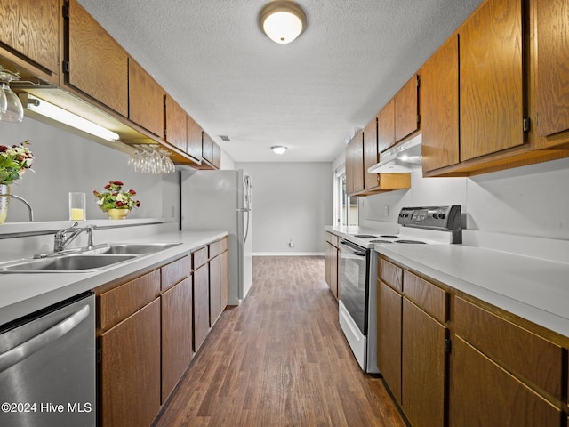 kitchen featuring dark hardwood / wood-style flooring, white appliances, a textured ceiling, and sink