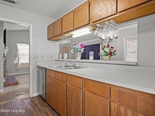 kitchen featuring an inviting chandelier, sink, stainless steel dishwasher, a textured ceiling, and dark hardwood / wood-style flooring