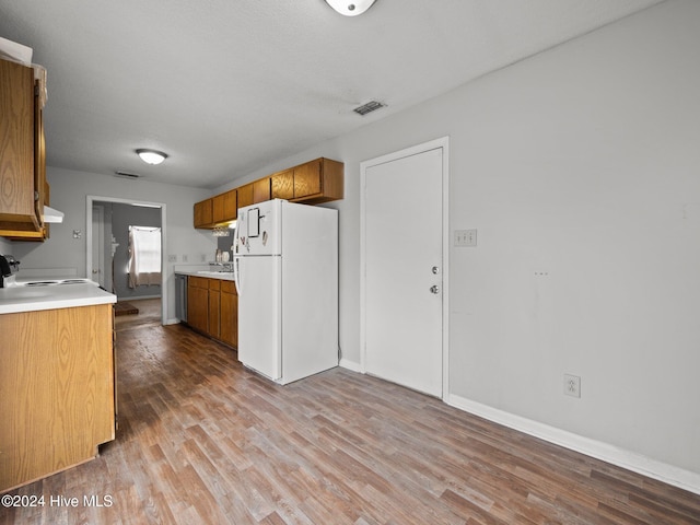 kitchen with stove, a textured ceiling, white fridge, and light hardwood / wood-style floors