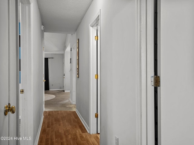 hall with hardwood / wood-style floors and a textured ceiling