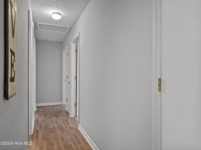 corridor featuring a textured ceiling and light wood-type flooring