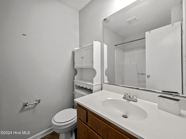 bathroom with vanity, toilet, a shower, and a textured ceiling