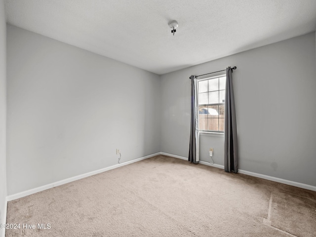 spare room featuring a textured ceiling and light carpet