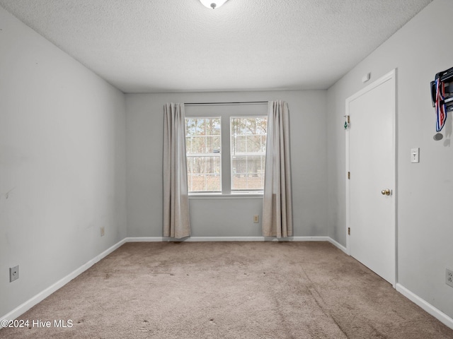 empty room featuring a textured ceiling and light colored carpet