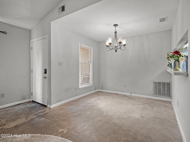 empty room with a notable chandelier, concrete floors, a textured ceiling, and vaulted ceiling