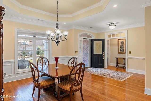 dining space with a tray ceiling, crown molding, hardwood / wood-style floors, and a chandelier