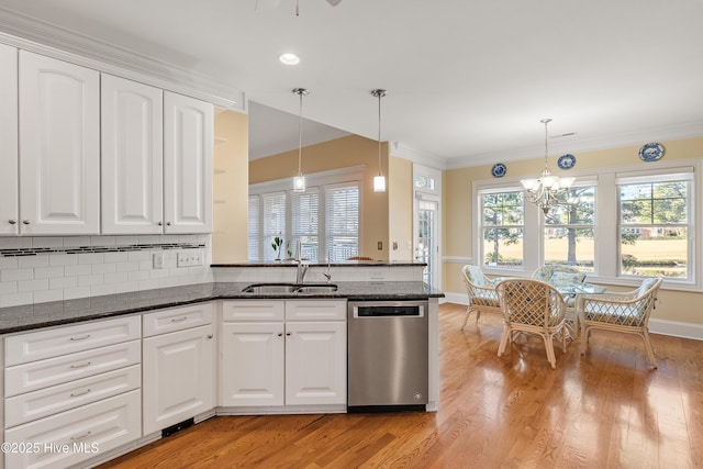 kitchen with white cabinetry, stainless steel dishwasher, kitchen peninsula, dark stone counters, and pendant lighting