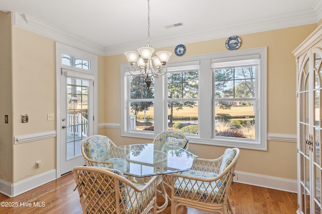 dining room with a chandelier, plenty of natural light, wood-type flooring, and ornamental molding