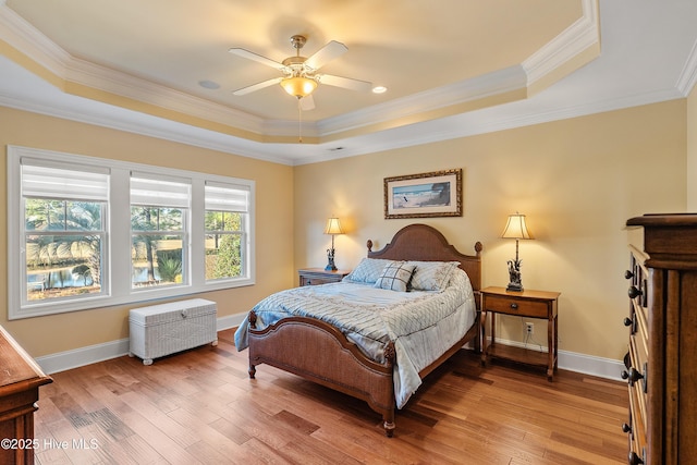 bedroom featuring light hardwood / wood-style floors, a raised ceiling, ceiling fan, and crown molding