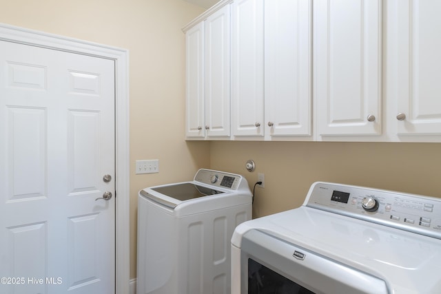 washroom with washing machine and clothes dryer and cabinets