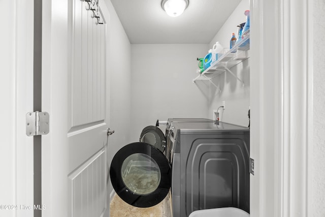 clothes washing area featuring a textured ceiling and washer and clothes dryer