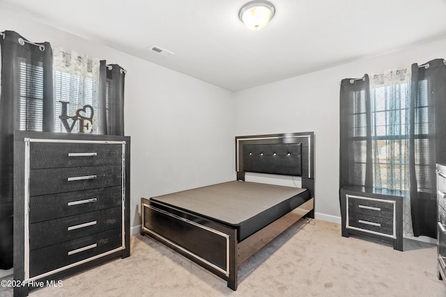 bedroom featuring light colored carpet and multiple windows