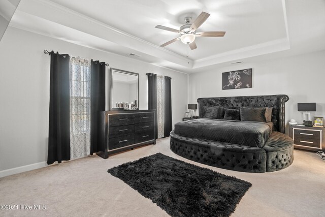 bedroom featuring a raised ceiling, ceiling fan, light colored carpet, and crown molding